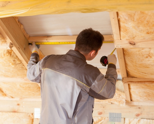 Back View Of Roofer Builder Worker With Ruler measuring